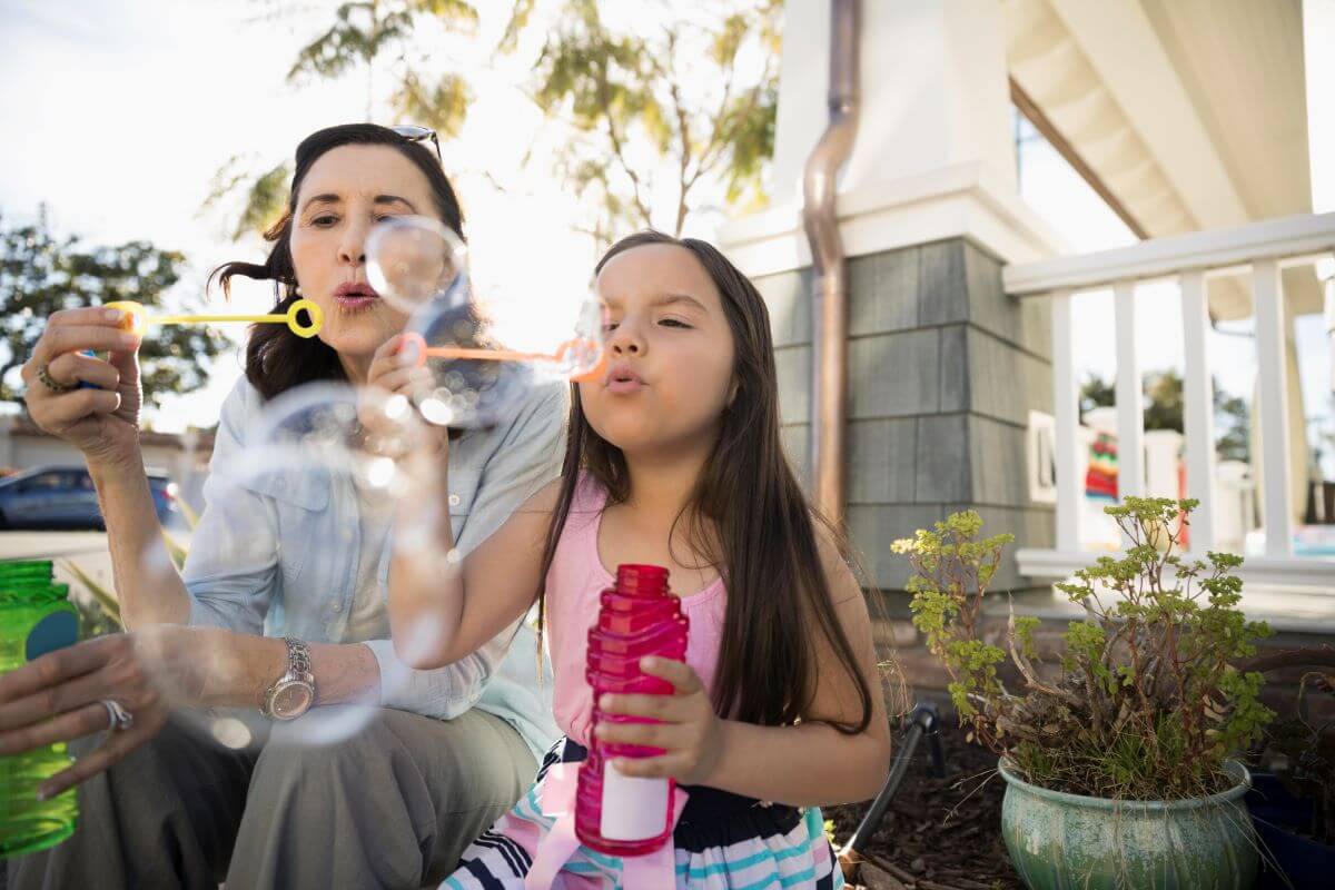 woman-blowing-bubbles-with-little-girl-outside woman-blowing-bubbles-with-little-girl-outside