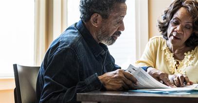 older-couple-reviewing-paperwork-at-kitchen-table