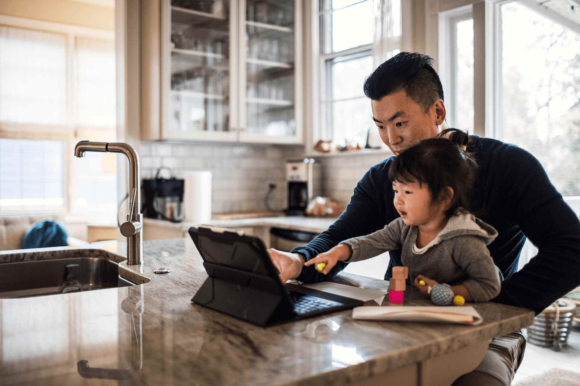 dad-and-daughter-on-tablet-at-kitchen-counter dad-and-daughter-on-tablet-at-kitchen-counter
